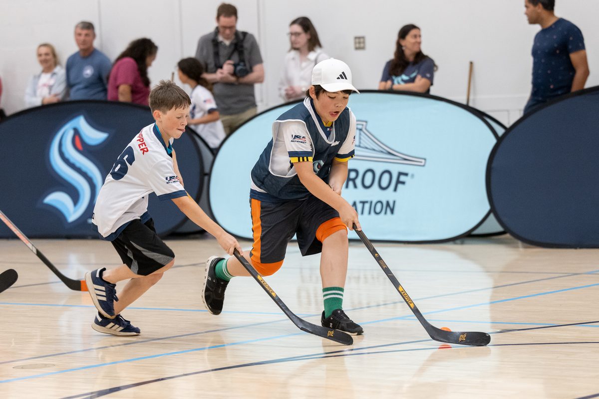 Two young ball hockey players battling for the ball