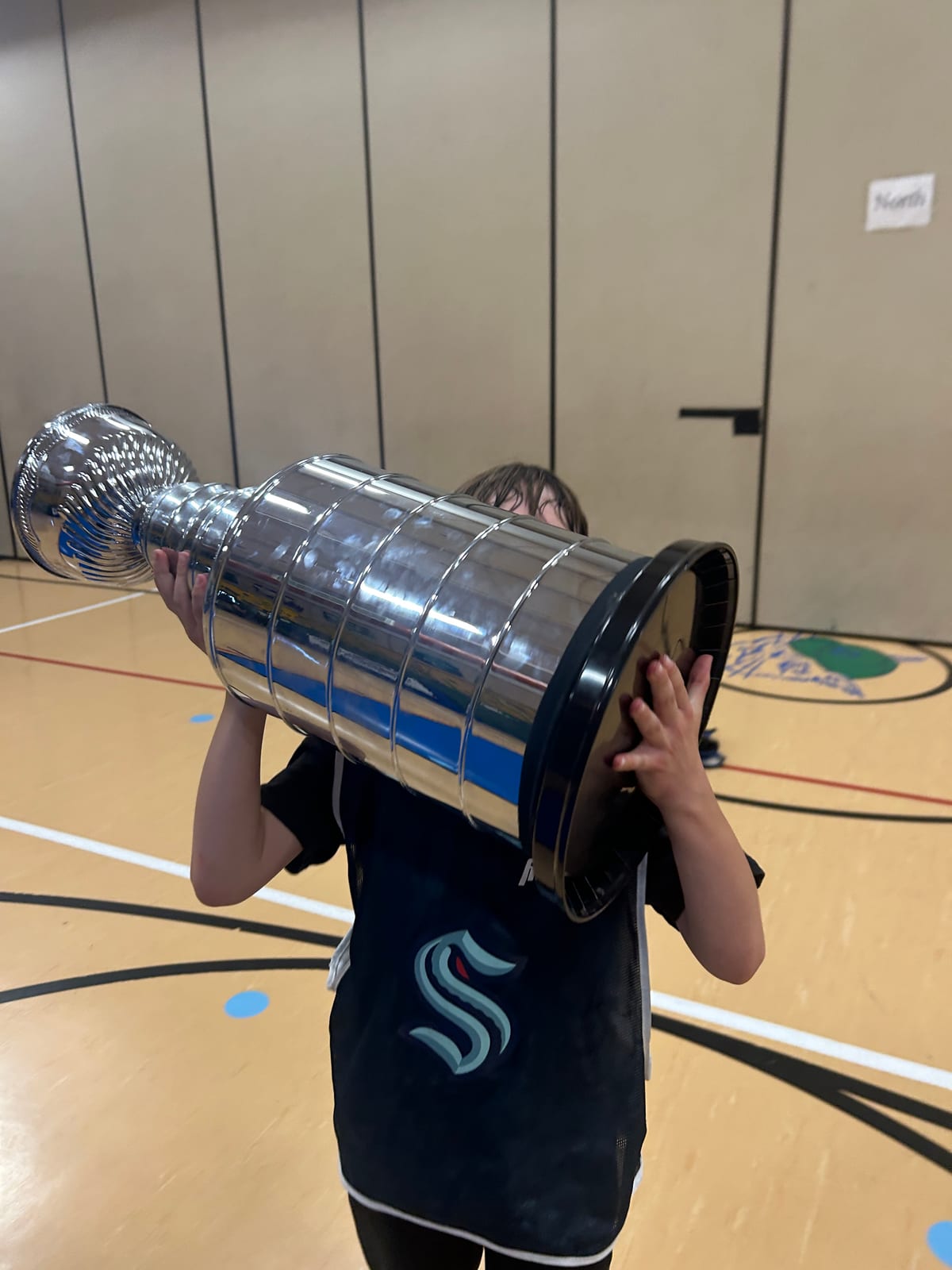 A young Emerald City player celebrating with a hockey trophy