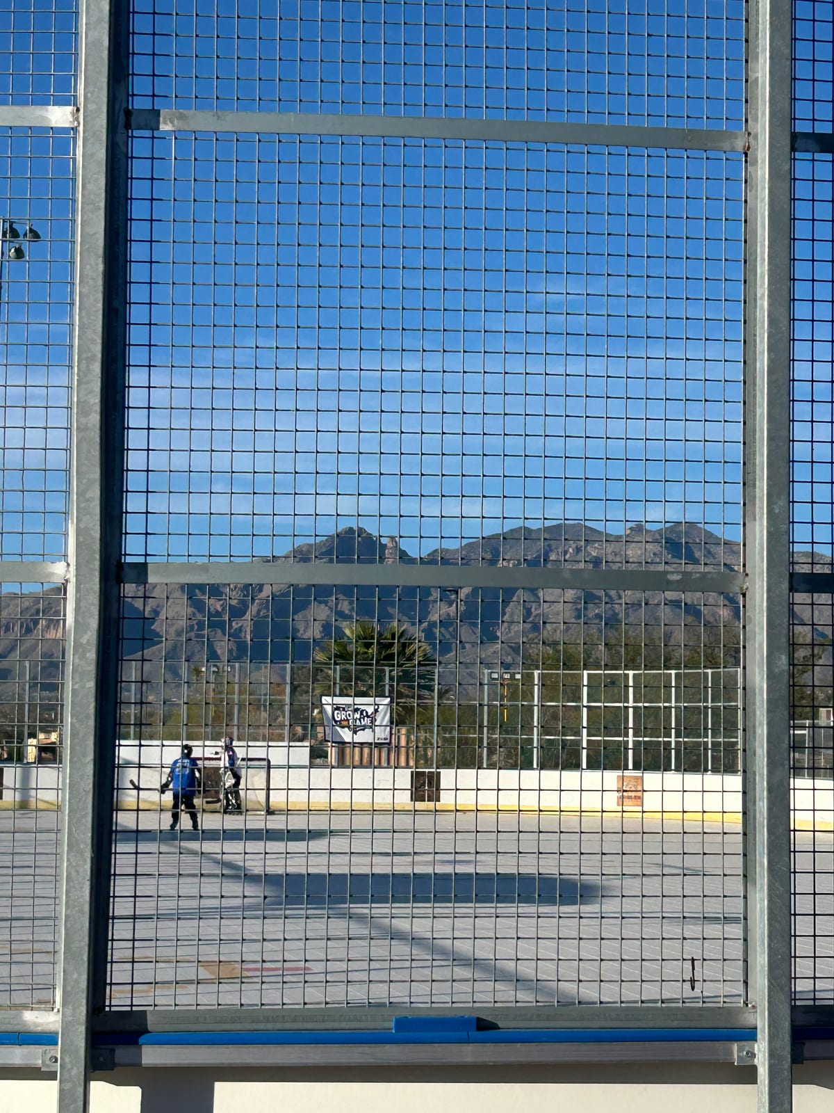 A community ball hockey rink set against a mountain backdrop